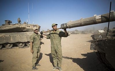Israeli soldiers clean the barrel of a tank cannon at a deployment area near the border with the Gaza Strip on August 2, 2014. (Yonatan Sindel/Flash90)