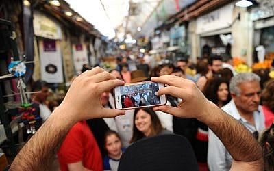 A visitor takes a cellphone picture at the Mahane Yehuda Market, in Jerusalem, on April 1, 2016. (Photo credit: Mendy Hechtman / Flash90)