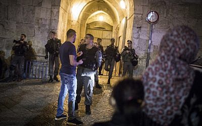 Palestinians wait outside Herod's Gate as security forces shut down the Old City of Jerusalem while searching for a suspect after a stabbing attack, on May 2, 2016. A Jewish man was stabbed and severely wounded (Hadas Parush/Flash90)