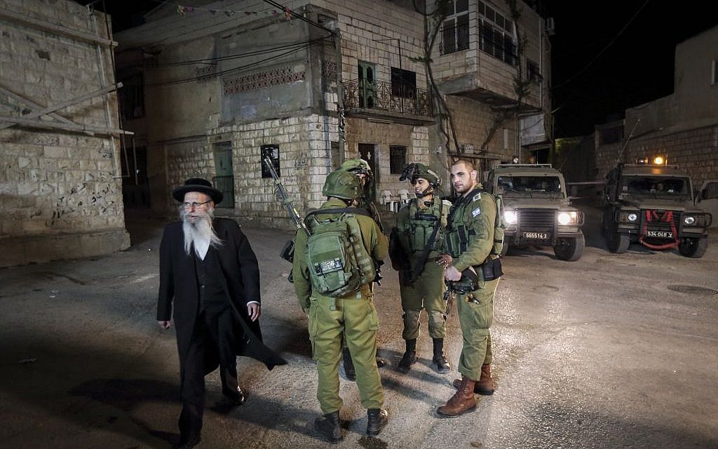 Soldiers stand guard as thousands of Ultra Orthodox Jewish men enter the Palestinian village of Kif al Harat, in the West Bank, accompanied by Israeli soldiers, to pray at the tombs of Yehoshua Ben Nun and Kalev Ben Yefune, on May 4, 2016. (Yaakov Naumi/Flash90)