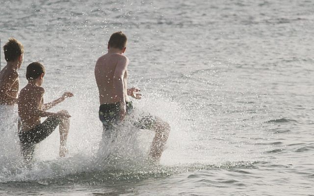 People frolic in the surf on a beach in Tel Aviv, on May 15, 2016. (Roni Schutzer/Flash90)