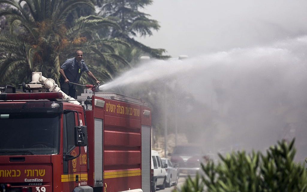 Fire fighters work to put out a fire that spread in the woods around Jerusalem's Ramot neighborhood May 26, 2016. (Yonatan Sindel/Flash90)