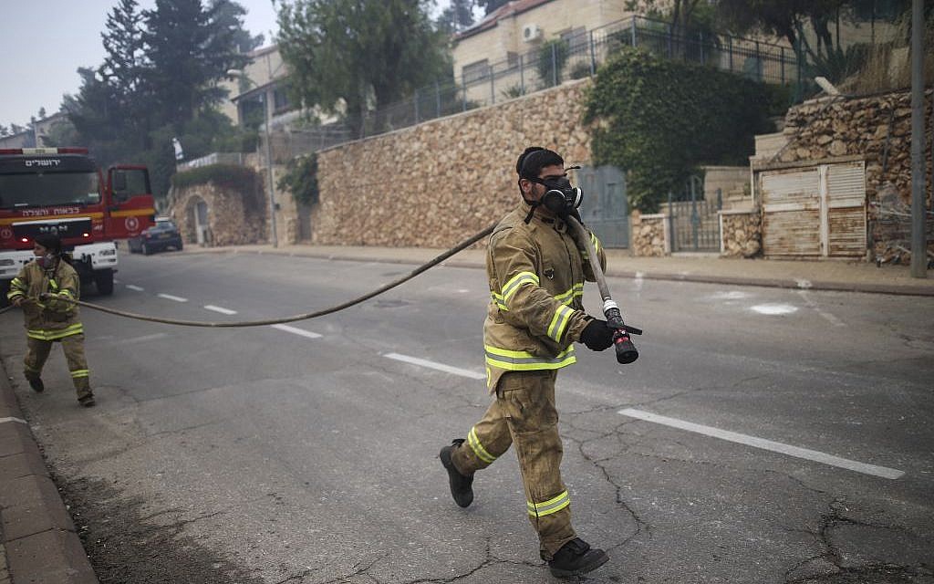 Illustrative: A firefighter works to put out a fire near the Jerusalem neighborhood of Ramot, on May 26, 2016. (Yonatan Sindel/Flash90)