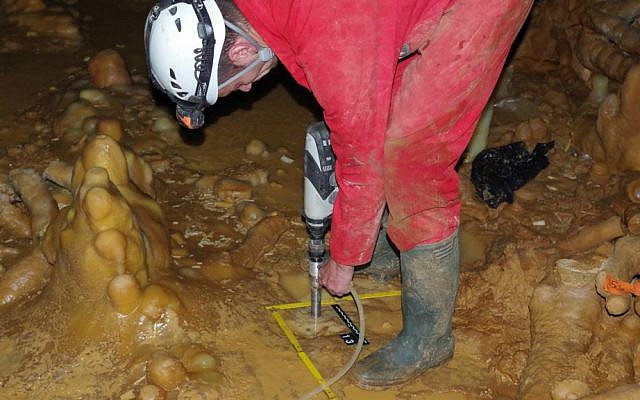 In this undated image released by CNRS on Wednesday May 25, 2016, a scientist drills into the floor of a cave containing the remains of structures built by Neanderthals, in Bruniquel, France. (Michel Soulier/CNRS via AP)