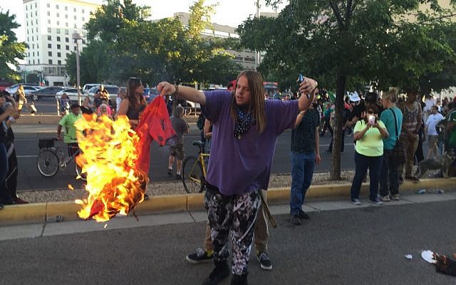 A protester holds a burning T-shirt as hundreds of people protest outside a rally for Republican presidential candidate Donald Trump in Albuquerque, New Mexico, May 24, 2016. (AP Photo/Russell Contreras)