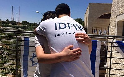 Shlomi Nachumson, youth director for the IDF Widows and Orphans Organization hugs an orphaned child at his home in the West Bank on May 11, 2016. (courtesy)