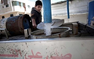 A Palestinian man fills tankers with drinking water for sale at a drinking water station in Gaza City, April 14, 2016. (AP Photo/Khalil Hamra)