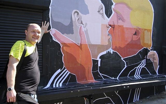 Restaurant owner Dominykas Ceckauskas poses next to a mural on the wall of his establishment depicting US Presidential hopeful Donald Trump and Russian President Vladimir Putin greeting each other with a kiss in the Lithuanian capital Vilnius on May 13, 2016 (AFP/Petras Malukas)