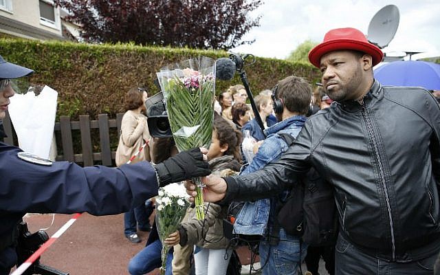 A police officer and a man hold a bouquet on June 15, 2016, outside the house in Magnanville where a man claiming allegiance to the Islamic State group killed a French policeman and his partner on the night of June 13. (AFP Photo/Matthieu Alexandre)