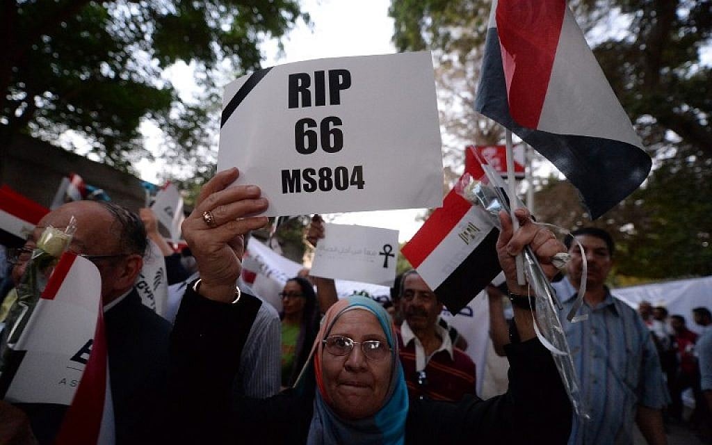 An Egyptian woman holds a poster and her national flag as she takes part in a march in the Egyptian capital of Cairo on May 26, 2016, for the 66 victims of the EgyptAir flight 804 that crashed into the Mediterranean Sea. (AFP/Khaled Desouki)