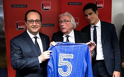 French President Francois Hollande (L) poses after receiving the jersey of former French soccer player Marius Tresor as a present from French Journalist Jacques Vendroux (C), as Radio France Director Mathieu Gallet looks on, following the public radio station France Inter's radio program 'L'Oeil du Tigre' (The Eye of the Tiger) at the Radio France headquarters in Paris on June 5, 2016 AFP PHOTO / POOL / ETIENNE LAURENT)