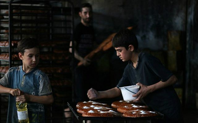 Syrian children help to prepare bread at a bakery in the rebel-held side of the northern city of Aleppo on June 6, 2016, as Muslims get ready for Iftar, or breaking of the daylong fast, on the first day of the holy month of Ramadan. (Thaer Mohammed/AFP)