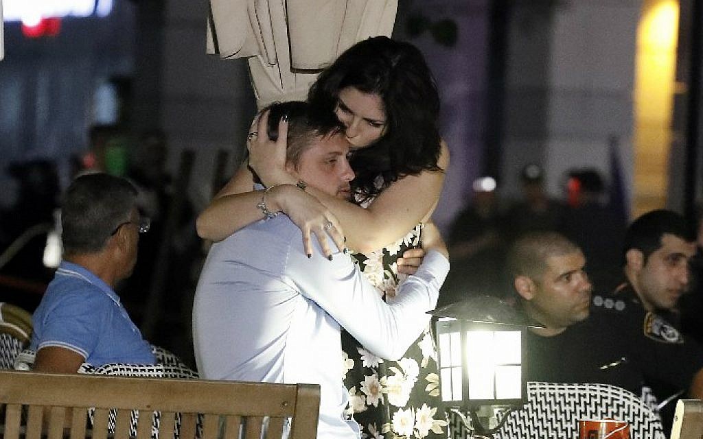 Israelis embrace following a shooting attack at the Sarona Market shopping complex in Tel Aviv on June 8, 2016. (Jack Guez/AFP)