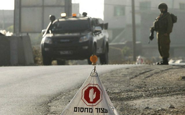 IDF soldiers man a temporary checkpoint at the entrance to the Palestinian village of Yatta in the southern West Bank on June 9, 2016 after the army entered the village in search of clues related to a shooting attack the previous night in Tel Aviv in which four people were killed and 16 others wounded. (Hazem Bader/AFP) IDF soldiers man a temporary checkpoint at the entrance to the Palestinian village of Yatta in the southern West Bank on June 9, 2016 after the army entered the village in search of clues related to a shooting attack the previous night in Tel Aviv in which four people were killed and 16 others wounded. (Hazem Bader/AFP)