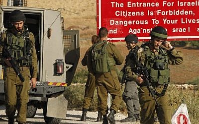Soldiers are seen at one of the entrances of the Palestinian village of Yatta, near Hebron, on June 9, 2016 (AFP/Hazem Bader)