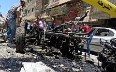 Syrians look at a burnt out vehicle used in a double bombing attack on June 11, 2016 outside the Sayeda Zeinab shrine, which is revered by Shiites around the world, some ten kilometers south of the center of Damascus, in the latest in repeated deadly strikes on the revered site. (AFP)