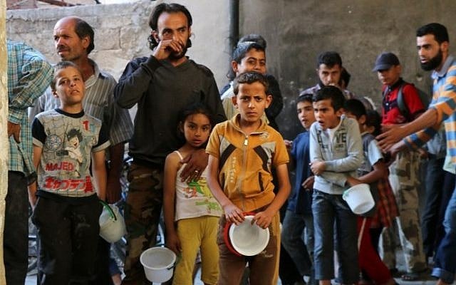 Syrians line-up waiting to receive meals distributed by the "Syria charity" NGO to impoverished families during the Muslim holy fasting month of Ramadan in a rebel-held neighborhood of the northern city Aleppo, June 11, 2016 . (AFP/THAER MOHAMMED)