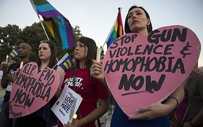 Mourners hold up signs during a vigil in Washington, DC on June 12, 2016, in reaction to the mass shooting at a gay nightclub in Orlando, Florida a day earlier. (AFP PHOTO/Andrew Caballero-Reynolds)