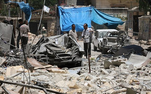 Syrian men look at the damage following reported air strikes the previous night on the rebel-held neighbourhood of al-Mashhad in the northern city of Aleppo, June 13, 2016. (AFP/AMEER ALHALBI)