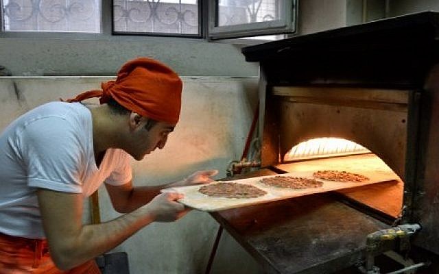 A picture taken on March 31, 2016 shows Kaits Jabakhchuryan, who came from Aleppo in 2012, baking lahmajoon -- a thin, crusty bread topped with ground meat -- at his restaurant in Yerevan. (AFP PHOTO / KAREN MINASYAN) A picture taken on March 31, 2016 shows Kaits Jabakhchuryan, who came from Aleppo in 2012, baking lahmajoon -- a thin, crusty bread topped with ground meat -- at his restaurant in Yerevan. (AFP PHOTO / KAREN MINASYAN)
