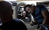 This photo taken on April 28, 2016 shows a Coptic Egyptian pilgrim (L) checking his new tattoo depicting Jesus Christ crucified on a cross, done by Christian Palestinian tattoo artist Walid Ayash (R) at his studio, in the West Bank town of Bethlehem. (AFP PHOTO / THOMAS COEX)