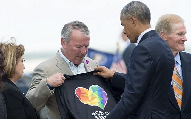 Orlando Mayor Buddy Dyer (L) holds an "Orlando United" T-shirt while greeting US President Barack Obama atthe Orlando International Airport in Orlando, Florida, June 16, 2016. (AFP PHOTO / SAUL LOEB)