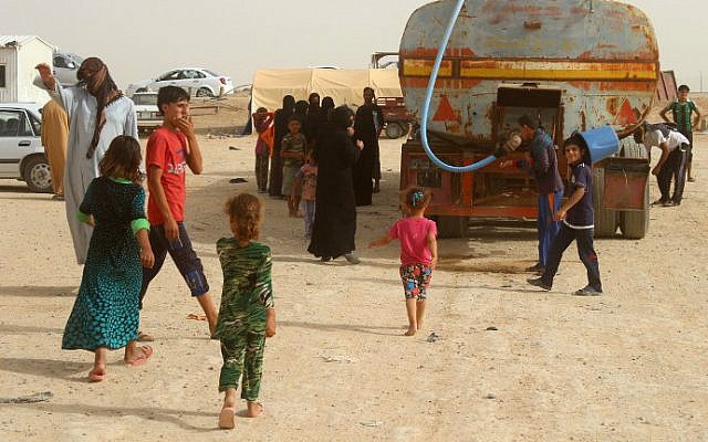Displaced Iraqis from the embattled city of Fallujah wait for water to be delivered at a camp suffering from water and food shortages where they are taking shelter some 18 kilometers from Ramadi on June 18, 2016. (Moadh al-Dulaimi/AFP)
