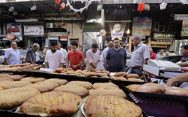 Syrians buy bread in Damascus' Midan neighborhood, which is renowned for it's sweet delicacies, as people shop prior to breaking their fast during the Muslim holy month of Ramadan on June 21, 2016. (AFP/LOUAI BESHARA)