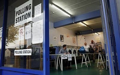 A woman collects her laundry before the polling station opens as a presiding officer and poll clerk set up a polling station in a laundromat in Headington outside Oxford on June 23, 2016. (AFP/ADRIAN DENNIS)
