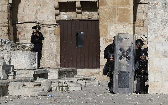 Israeli police take cover as Palestinian protesters throw stones at them at Jerusalem's Temple Mount compound during clashes between Israeli police and Muslims for the third consecutive day on June 28, 2016 in Jerusalem's Old City. (AFP/AHMAD GHARABLI)