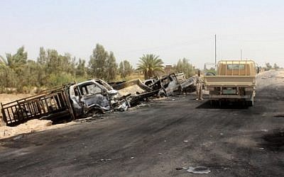 A member of the Iraqi government forces stands next to the charred vehicles on a road southwest of Fallujah after Iraqi forces airstrikes destroyed 260 vehicles carrying militants from the Islamic State group trying to flee after their defeat in Fallujah, June 29, 2016. (AFP/MOADH AL-DULAIMI)
