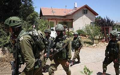 Israeli soldiers stand guard outside a house in the Jewish settlement of Kiryat Arba where a 13-year-old Israeli girl was fatally stabbed in her bedroom on June 30, 2016. (AFP/MENAHEM KAHANA)