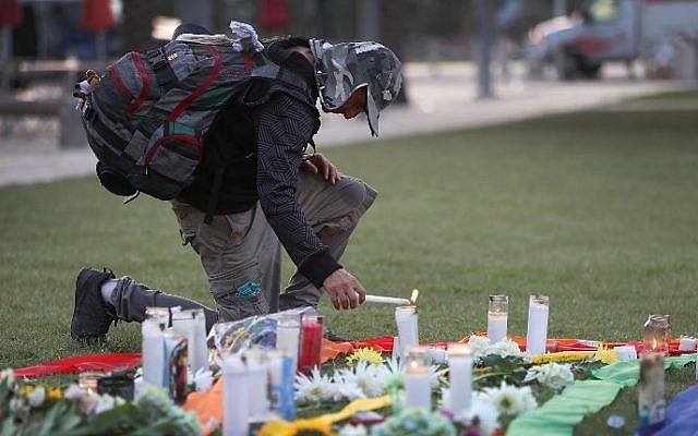 A man lights a candle as he pays his respects at a memorial in front the Dr. Phillips Center for the Performing Arts to the victims of the Pulse gay nightclub shooting where Omar Mateen allegedly killed 49 people on June 14, 2016 in Orlando, Florida. Joe Raedle/Getty Images/AFP)