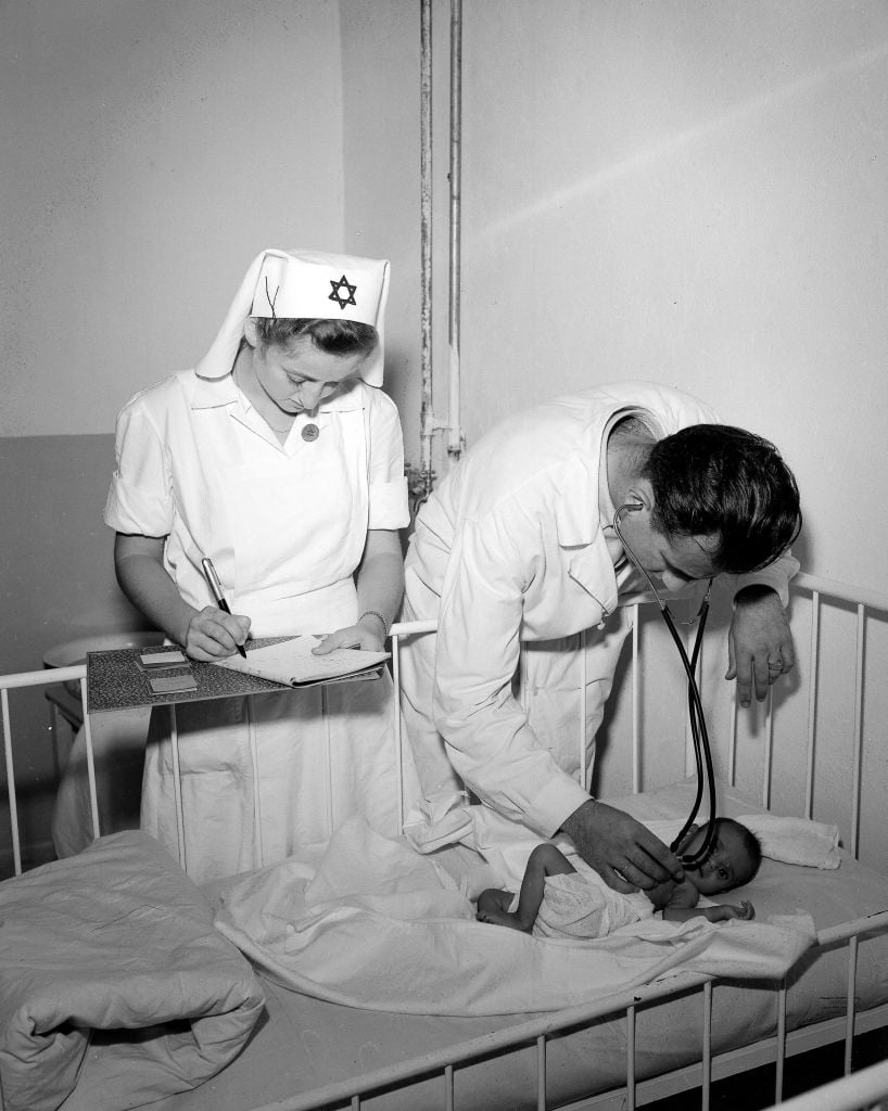 An Israeli doctor examines an undernourished immigrant baby in 1949 (Teddy Brauner/GPO)
