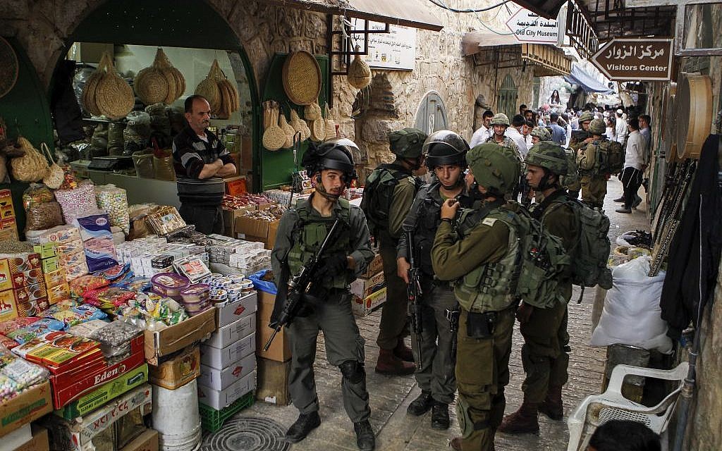 Israeli troops stand guard as settlers take a tour in the contested West Bank city of Hebron, on June 4, 2016. (Wisam Hashlamoun/Flash90)