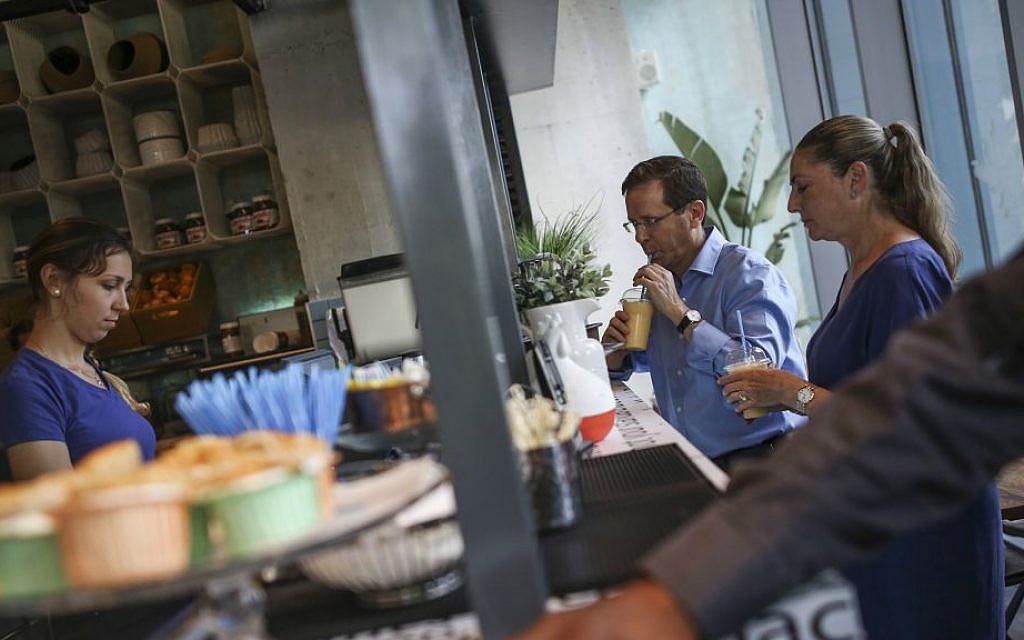 Opposition leader MK Isaac Herzog and his wife Michal show their support by buying coffee at the Sarona Market shopping center in Tel Aviv on June 9, 2016, the morning after a fatal terror attack at the site. (Miriam Alster/Flash90)