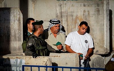 Palestinians submit their ID cards for inspection at a checkpoint in the West Bank city of Bethlehem, as they head to the Al-Aqsa Mosque in Jerusalem for the first Friday prayers of Ramadan on June 10, 2016. (Photo by Wisam Hashlamoun/FLASH90)