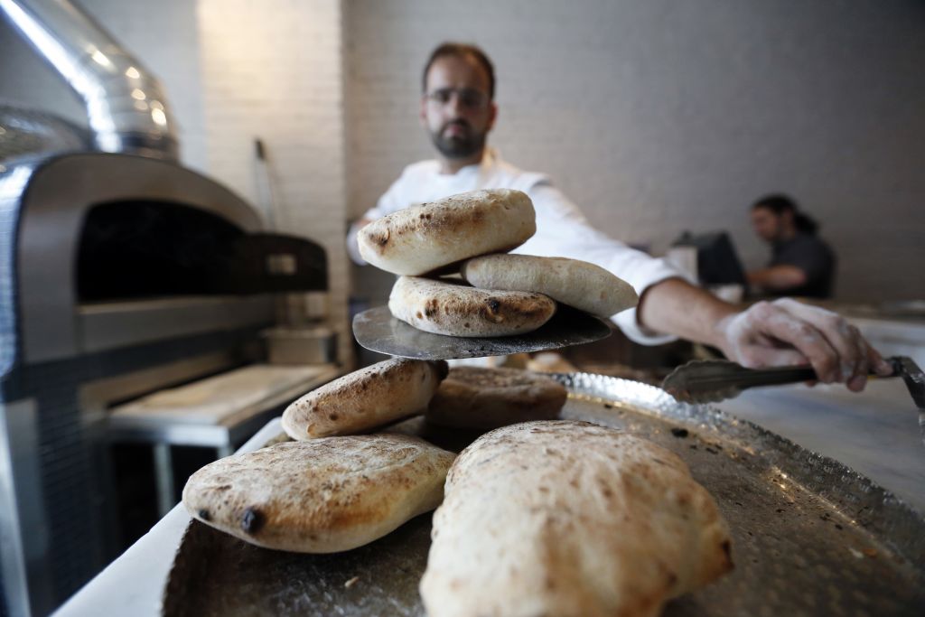 In this Tuesday, May 31, 2016 photo, Chef Alon Shaya, proprietor of Shaya Restaurant, makes house made pita at his wood fired oven at the restaurant in New Orleans. (AP Photo/Gerald Herbert) In this Tuesday, May 31, 2016 photo, Chef Alon Shaya, proprietor of Shaya Restaurant, makes house made pita at his wood fired oven at the restaurant in New Orleans. (AP Photo/Gerald Herbert)