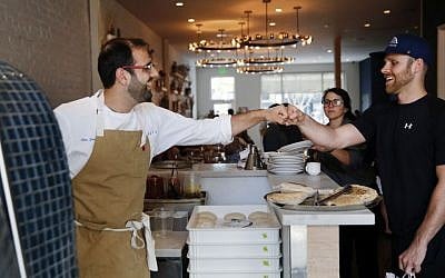 Chef Alon Shaya (left), proprietor of Shaya Restaurant, fist-pumps a customer who complimented him at his restaurant in New Orleans, May 31, 2016. (AP/Gerald Herbert)
