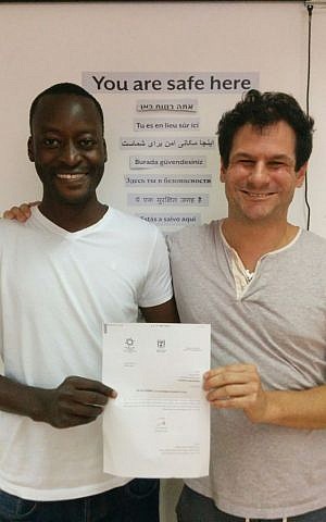 Mutasim Ali, left, and his lawyer Asaf Weitzen, with the announcement of refugee status from the Interior Ministry on June 23, 2016. (courtesy Hotline for Refugees and Migrants) Mutasim Ali, left, and his lawyer Asaf Weitzen, with the announcement of refugee status from the Interior Ministry on June 23, 2016. (courtesy Hotline for Refugees and Migrants)