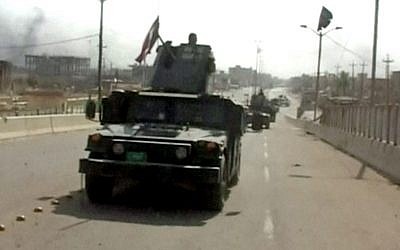 A still image from video of Iraqi troops carrying Iraqi flags on their vehicles after a senior Iraqi commander declared that the city of Fallujah was "fully liberated" from Islamic State group militants, in Fallujah, Iraq, June 26, 2016. (AP Video via AP)