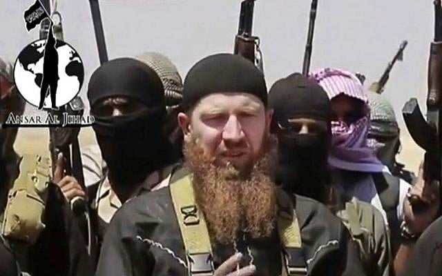 This file image made from undated video posted during the weekend of June 28, 2014 on a social media account frequently used for communications by the Islamic State shows Omar al-Shishani standing next to the group's spokesman among a group of fighters as they declare the elimination of the border between Iraq and Syria. (AP Photo/militant social media account via AP video)