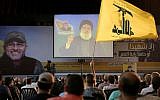 A Hezbollah supporter waves his group's flag, as Hezbollah leader Hassan Nasrallah, center, speaks via a video link, in the southern suburb of Beirut, Lebanon, Friday, June 24, 2016.  (AP Photo/Hussein Malla)