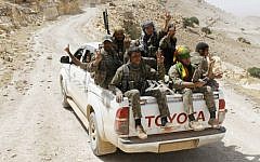 Kurdish fighters of the YPG flash victory signs as they sit on their pickup on their way to battle against the Islamic State, near Kezwan mountain, northeast Syria, May 20, 2015. (The Kurdish fighters of the People's Protection Units via AP/File)
