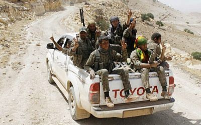 In this file photo released on May 20, 2015, provided by the Kurdish fighters of the People's Protection Units (YPG), Kurdish fighters of the YPG flash victory signs as they sit on their pickup on their way to battle against the Islamic State, near Kezwan mountain, northeast Syria. (The Kurdish fighters of the People's Protection Units via AP, File) In this file photo released on May 20, 2015, provided by the Kurdish fighters of the People's Protection Units (YPG), Kurdish fighters of the YPG flash victory signs as they sit on their pickup on their way to battle against the Islamic State, near Kezwan mountain, northeast Syria. (The Kurdish fighters of the People's Protection Units via AP, File)