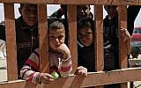 Syrian refugees look through the gate of a grocery store at the al-Azraq refugee camp in northeast Jordan, April 14, 2016. (AP Photo/ Sam McNeil)