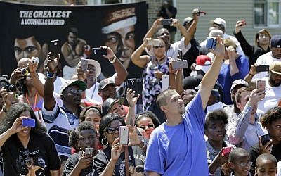 People watch as the funeral procession for Muhammad Ali passes in front of his boyhood home Friday, June 10, 2016, in Louisville, Ky. (Mark Humphrey/AP)