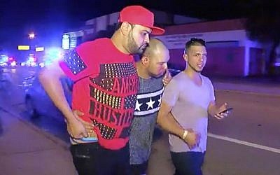 An injured man is escorted out of the Pulse nightclub after a shooting rampage, Sunday morning June 12, 2016, in Orlando, Fla. (AP/Steven Fernandez)