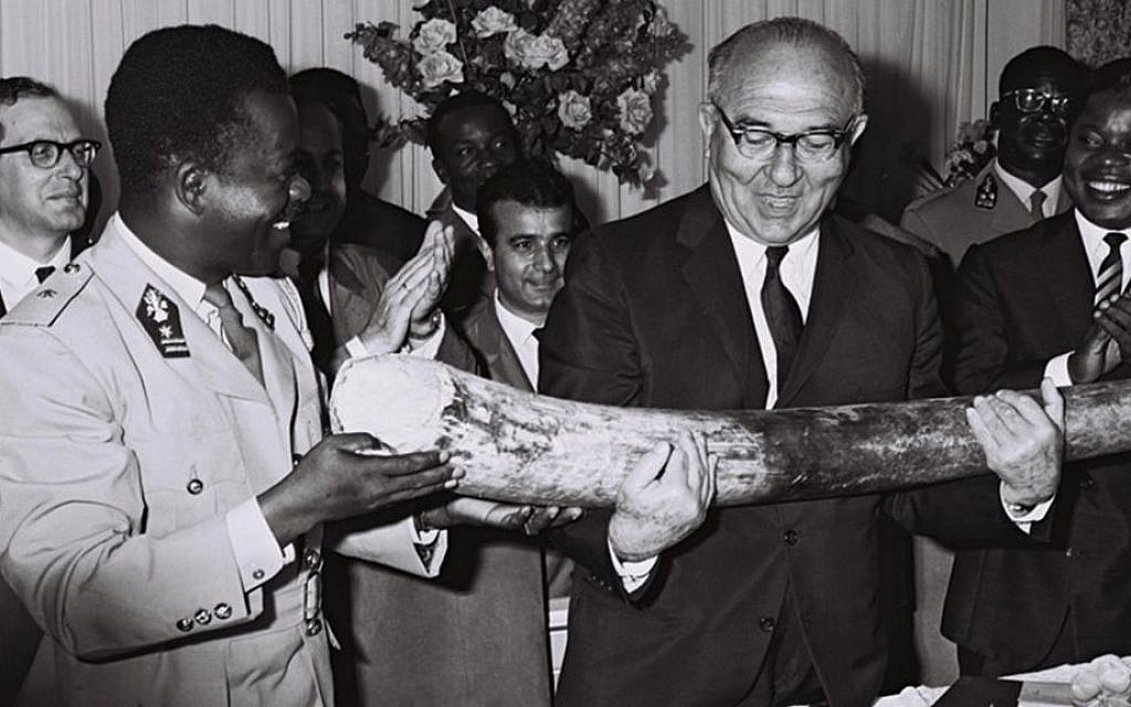 Congolese premier Gen. Leonard Mulamba gives Prime Minister Levi Eshkol an elephant tusk in a ceremony outside Kinshasa, June, 1966. (Moshe Fridan/GPO)