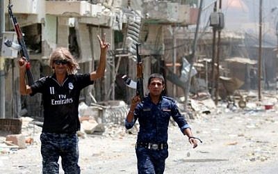 Members of Iraqi police forces celebrate on a street on June 27, 2016 in western Fallujah, 50 kilometers (30 miles) from the Iraqi capital Baghdad, after Iraqi forces retook the embattled city from the Islamic State group. (AFP PHOTO / HAIDAR MOHAMMED ALI)